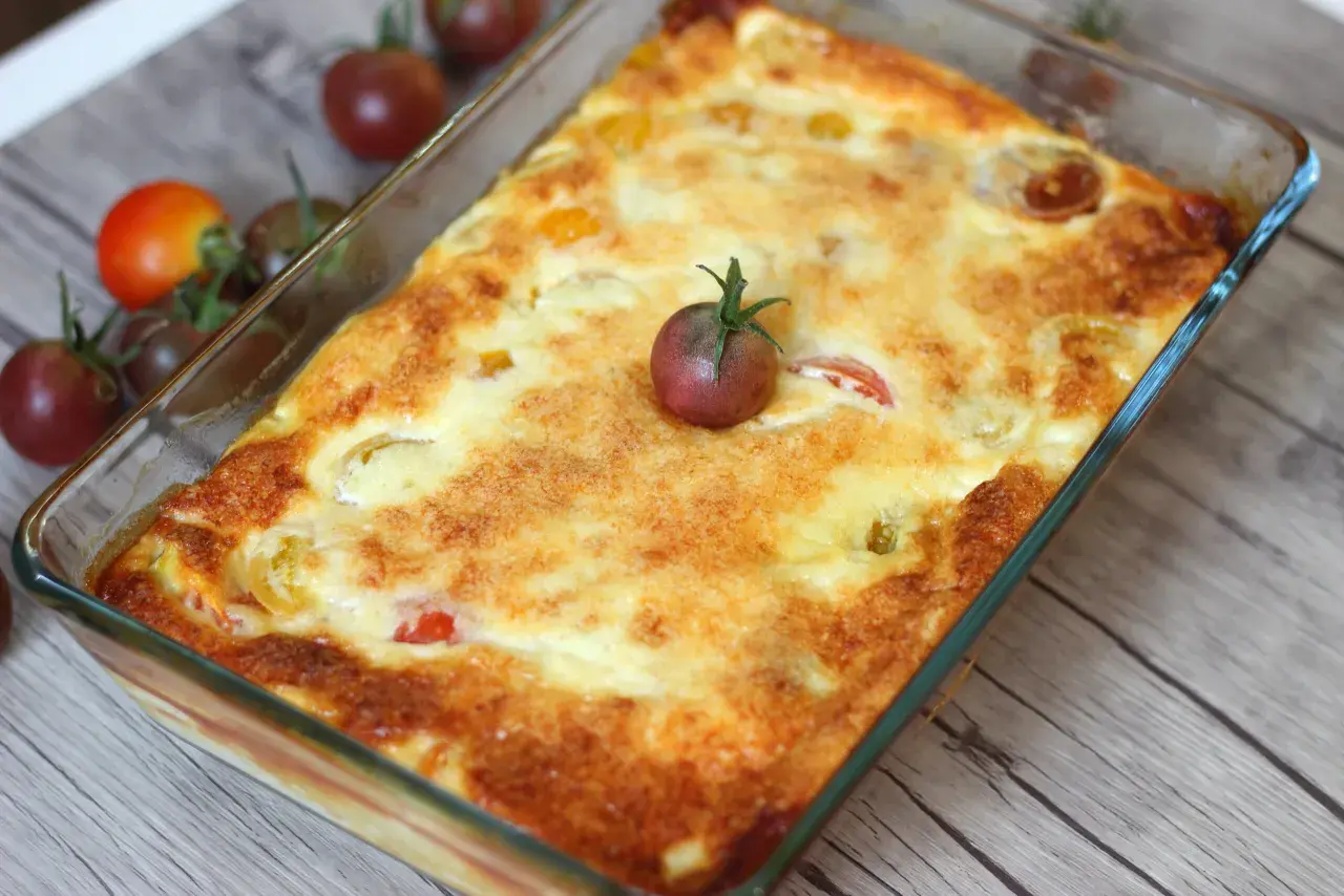 Un clafoutis tomates cerises doré et appétissant, garni d'une tomate cerise fraîche, prêt à être dégusté.
