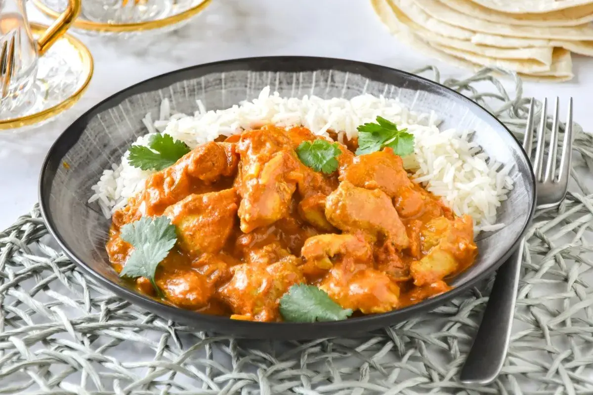 Un delicioso pollo tikka masala receta servido con arroz basmati y cilantro fresco.