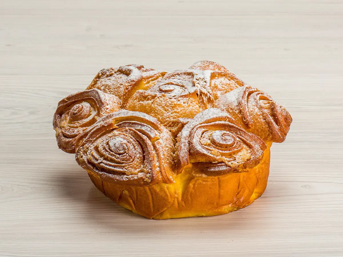 Una torta delle rose dorata e soffice, cosparsa di zucchero a velo, pronta per essere gustata.