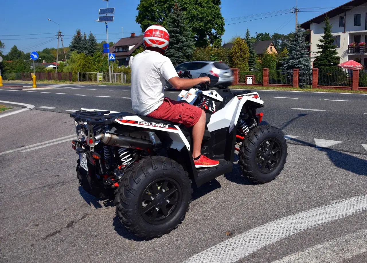 Mężczyzna w kasku na quadzie Polaris na drodze. Czy na quadzie trzeba mieć kask? Tak, dla bezpieczeństwa!