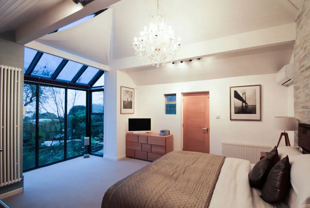 Habitación moderna con grandes ventanales que dan a un jardín. Ideas para como hacer un balcón en una casa ya construida.