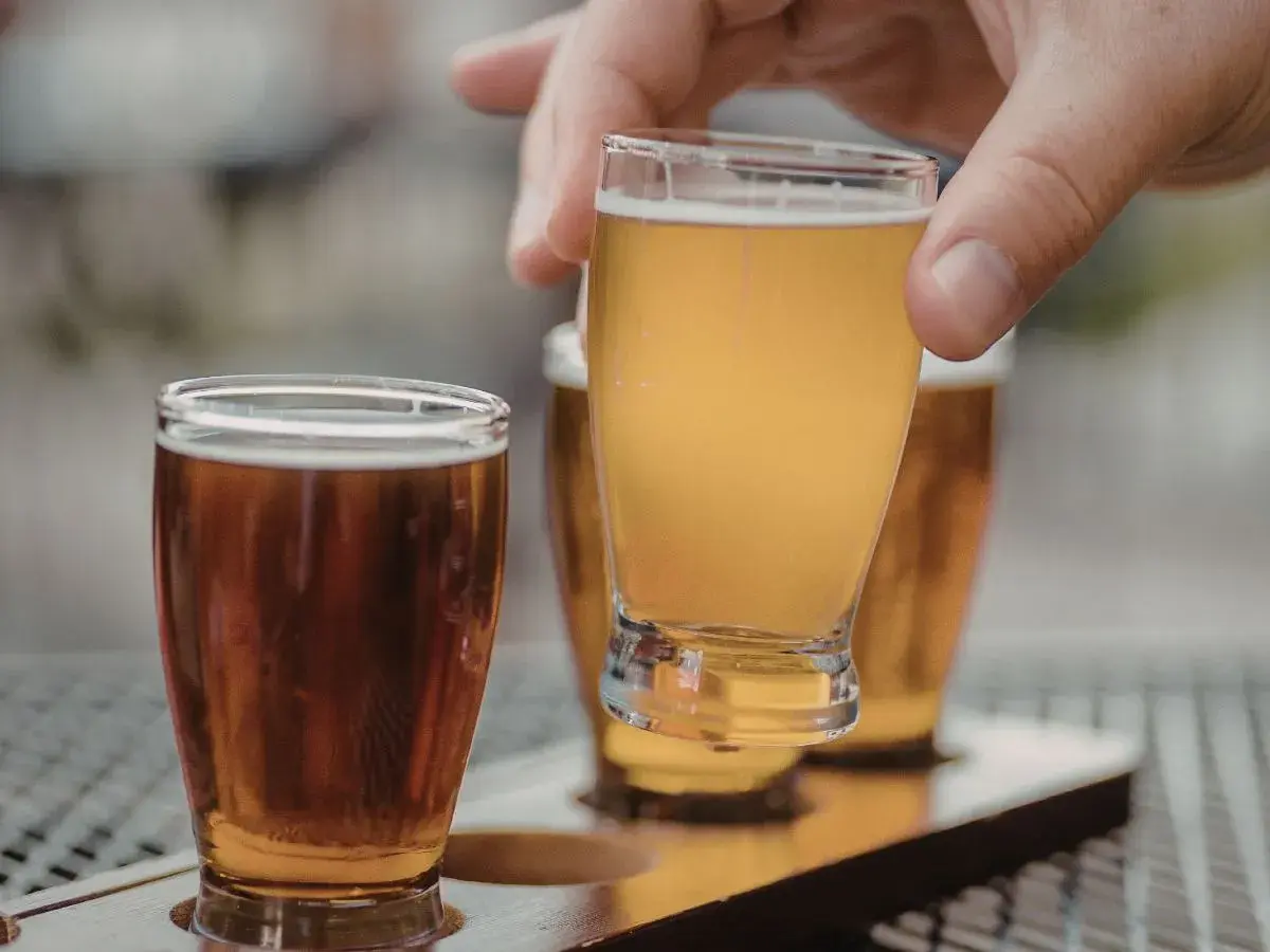 Assaggio di una fresca italian pale ale dorata, con un'altra birra ambrata in primo piano.