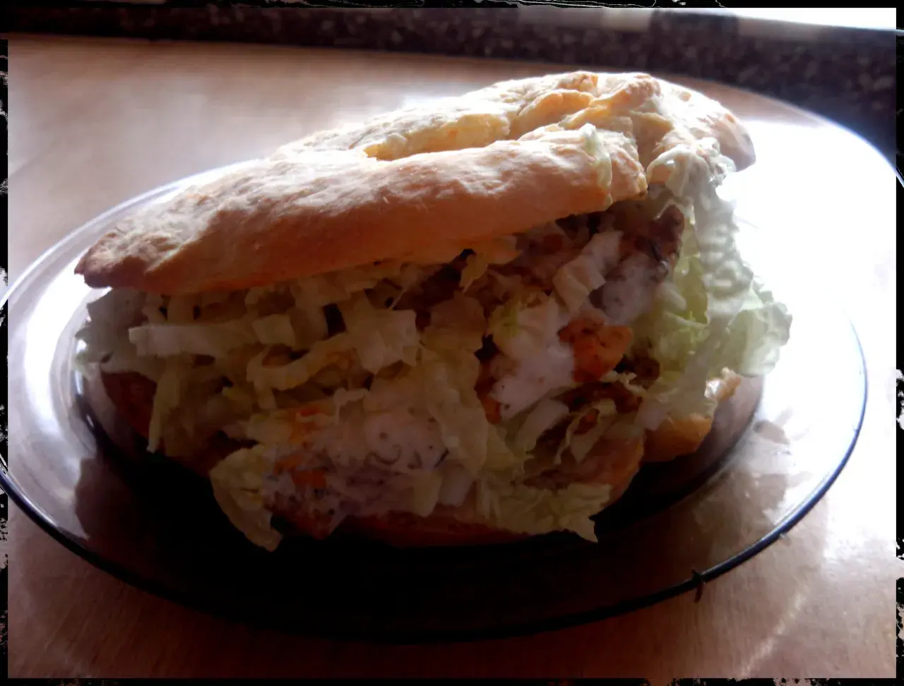 Pyszny kebab w bułce z chrupiącą sałatą i kremowym sosem, gotowy do zjedzenia.