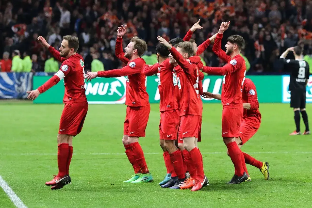 Piłkarze w czerwonych strojach świętują zwycięstwo w Pucharze Francji.