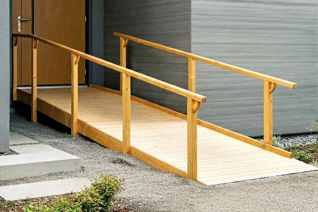 Eine stabile Holz-Rollstuhlrampe, die man selber bauen kann, mit Geländer führt zur Haustür.