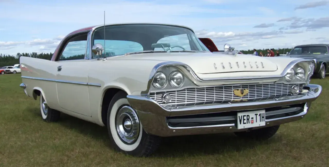 Vit Chrysler 58 med rött tak, blanka kromdetaljer och vit sidovägg på däcken. Bilen står på en gräsmatta.