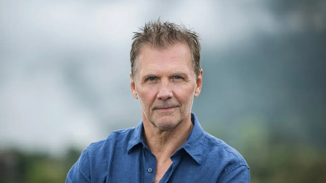 Johan Gullberg, en man med väderbitet ansikte och rufsig frisyr, bär en blå skjorta. En bild som väcker tankar, nästan som en flashback.