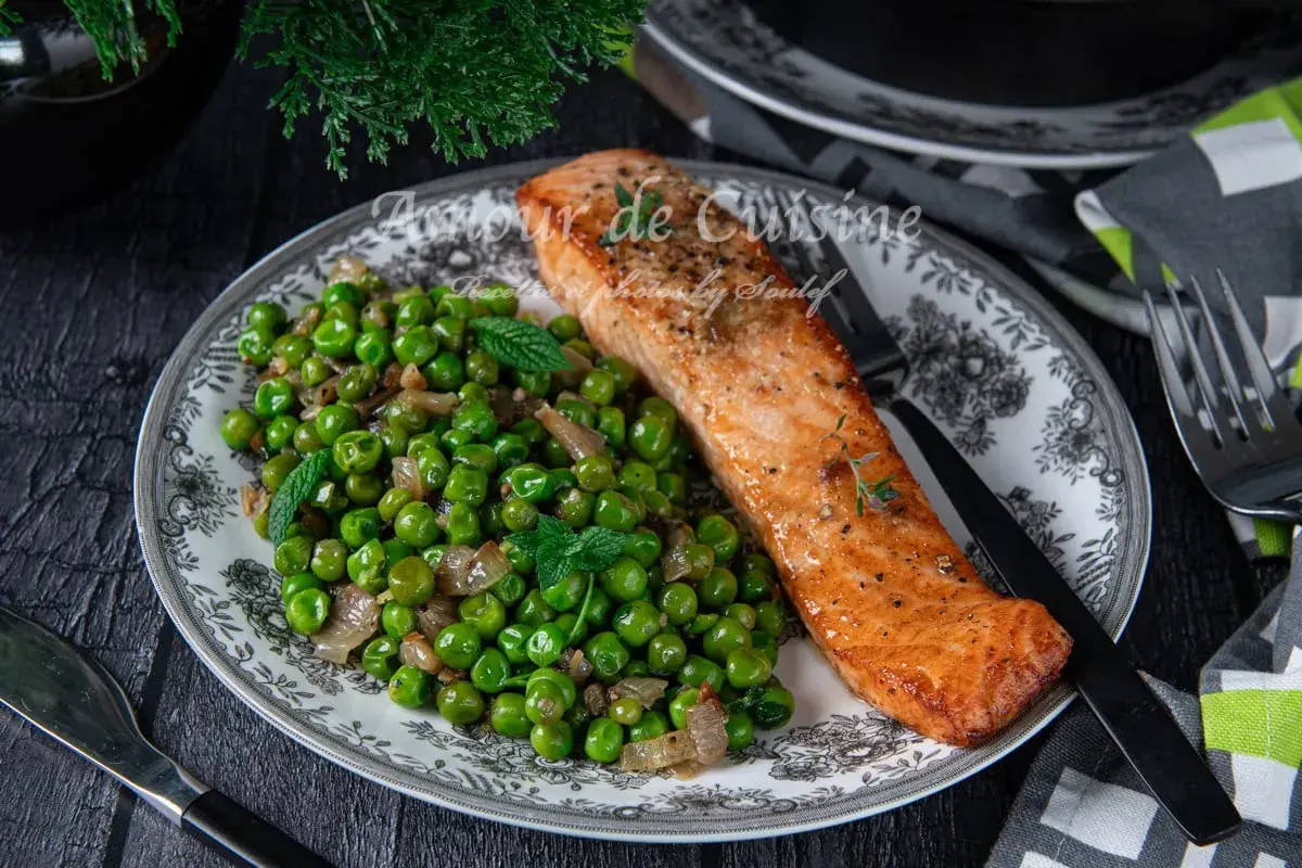 Filet de saumon poêlé servi avec une poêlée de petits pois et oignons, garnie de menthe fraîche. Une recette simple et savoureuse.