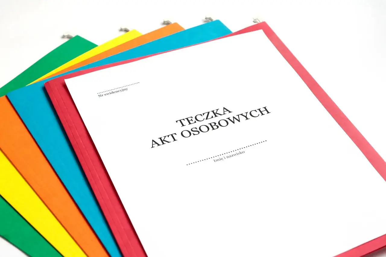 Kolorowe teczki z dokumentami, jedna z nich to Teczka Akt Osobowych część A, gotowa do wypełnienia.