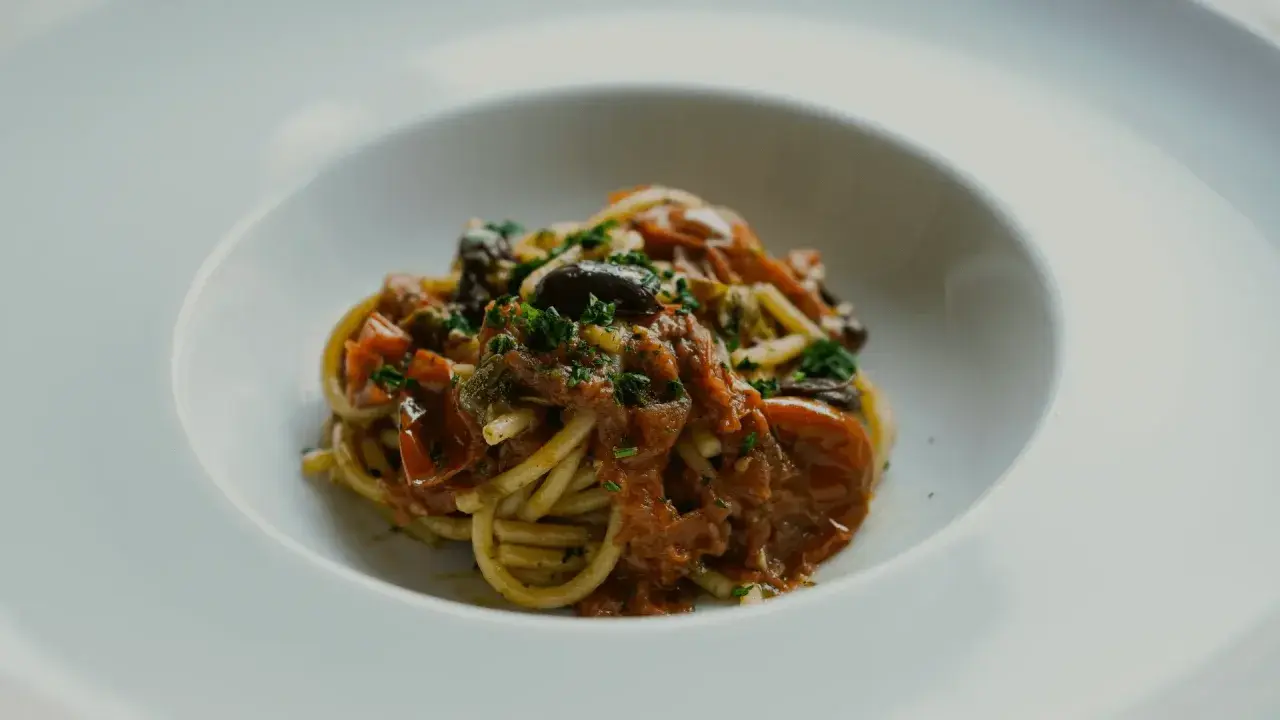 En portion spaghetti med en smakrik tomatsås, oliver och kapris. Perfekt vin till pasta puttanesca.