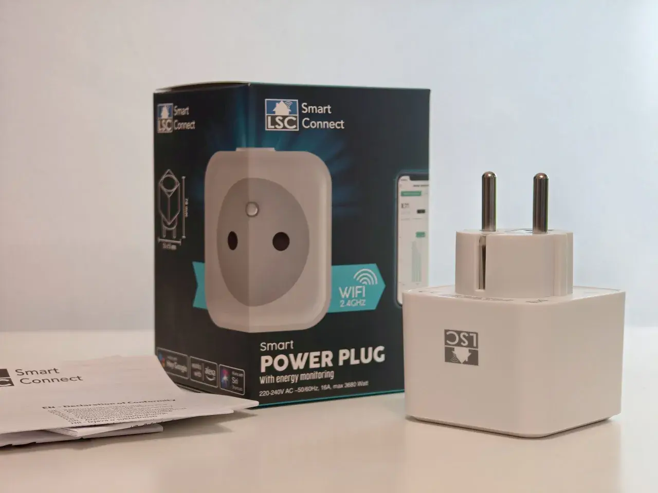 Inteligentne gniazdko LSC Smart Connect z monitorowaniem energii, obok pudełka i instrukcji.
