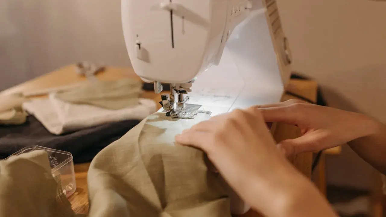 Hands guide fabric through a sewing machine, a peaceful scene of a sewing hobby.