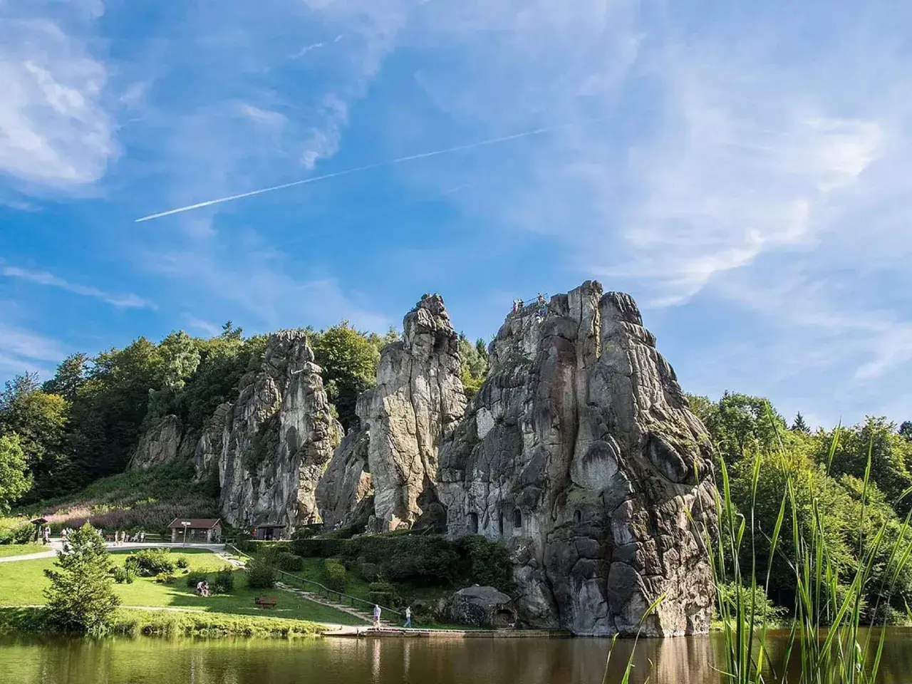 Felsformationen am Wasser, umgeben von grünen Bäumen, ein Ort, der an magische Orte in Deutschland erinnert.