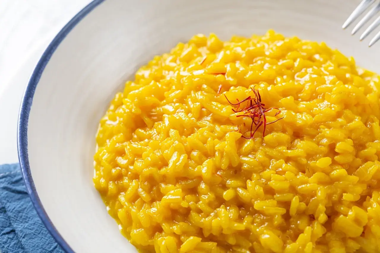 Risotto alla Milanese, un classico tra i piatti tipici lombardi, cremoso e profumato allo zafferano, guarnito con pistilli rossi.