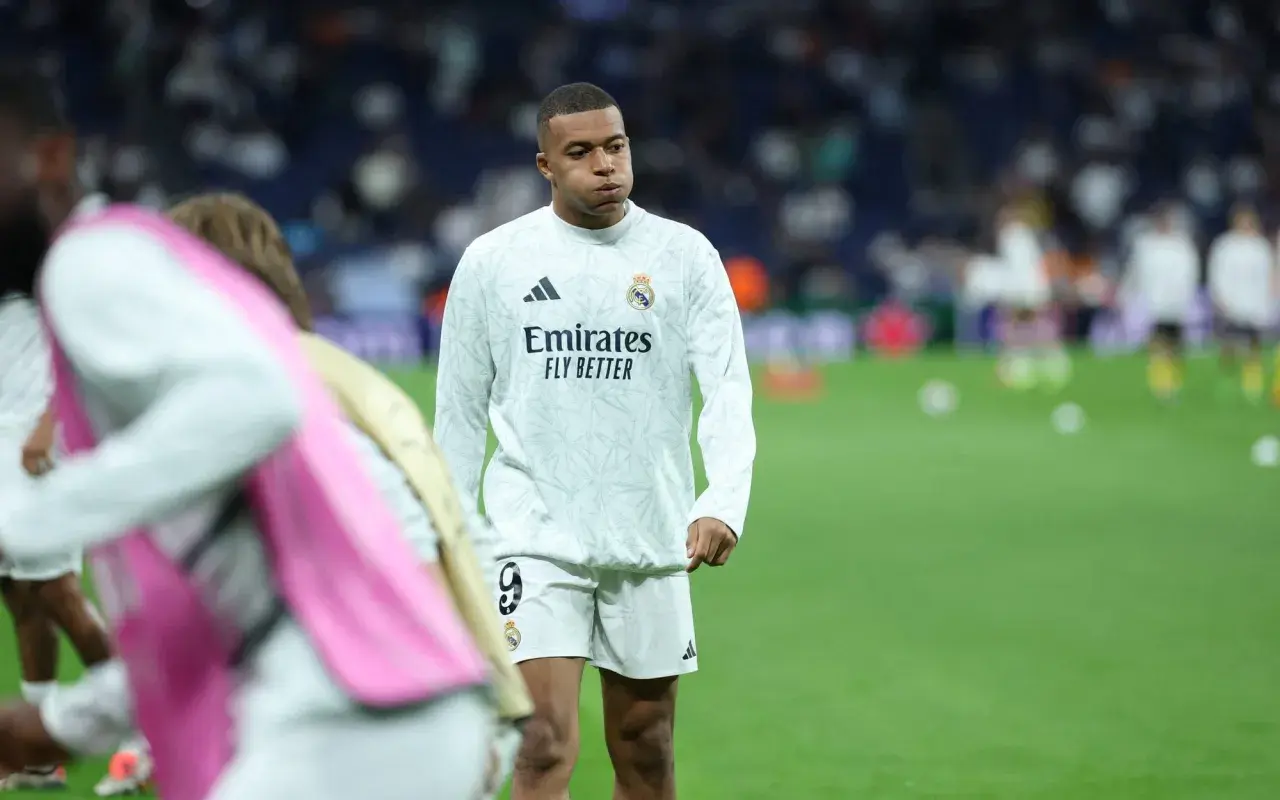 Mbappé, młody piłkarz Realu Madryt, w białej koszulce treningowej z logo Emirates.