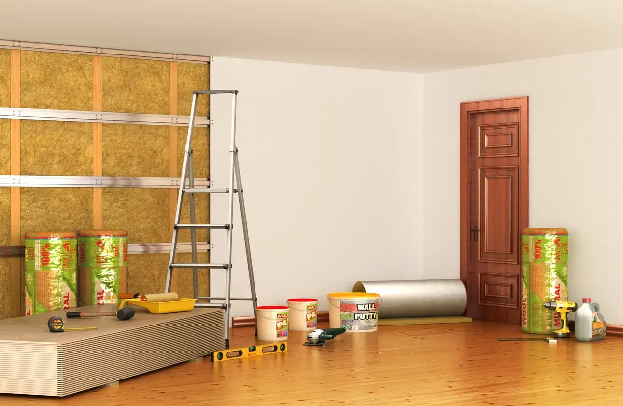 Materiali per isolamento termico e acustico, inclusi rotoli di lana minerale per un efficace cappotto interno antimuffa. Attrezzi da lavoro e pannelli pronti per l'installazione.