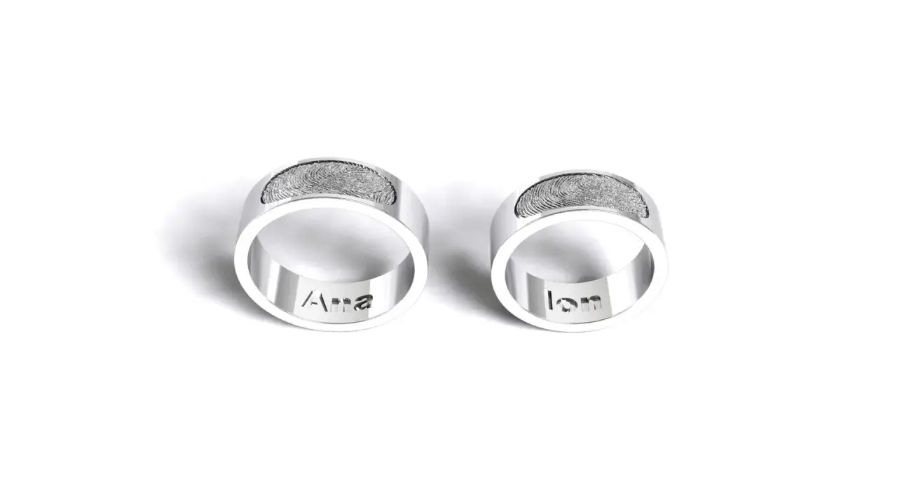 Dos anillos de plata grabados con huellas dactilares y nombres: "Ana" y "Ian". Un símbolo de amor eterno para rodear el dedo.