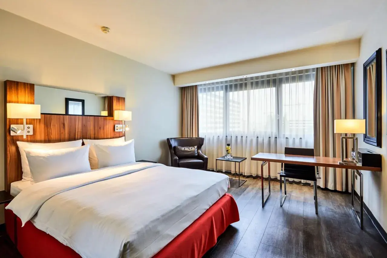 Przytulny pokój w hotelu Radisson Blu Scandinavia Hotel Dusseldorf z wygodnym łóżkiem, fotelem i biurkiem.