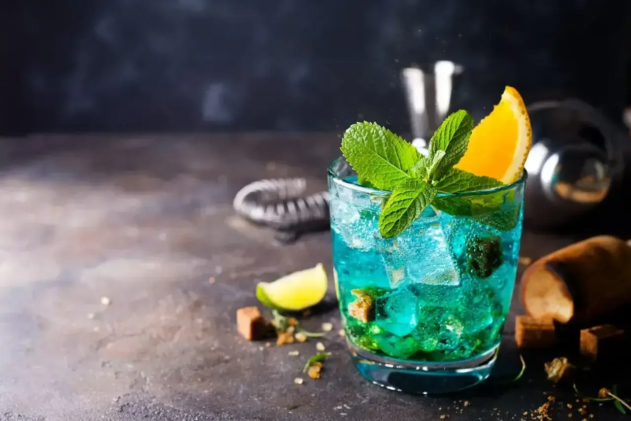 Orzeźwiający drink Blue Lagoon z miętą i pomarańczą, idealny na letnie wieczory.