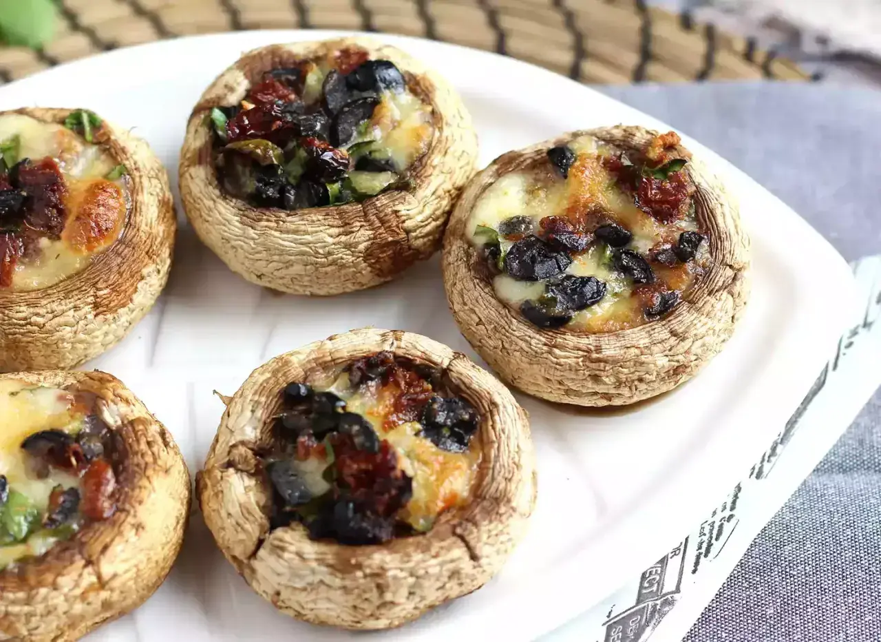 Champignons farcis aux olives et tomates séchées, gratinés au fromage. Un délice à déguster !