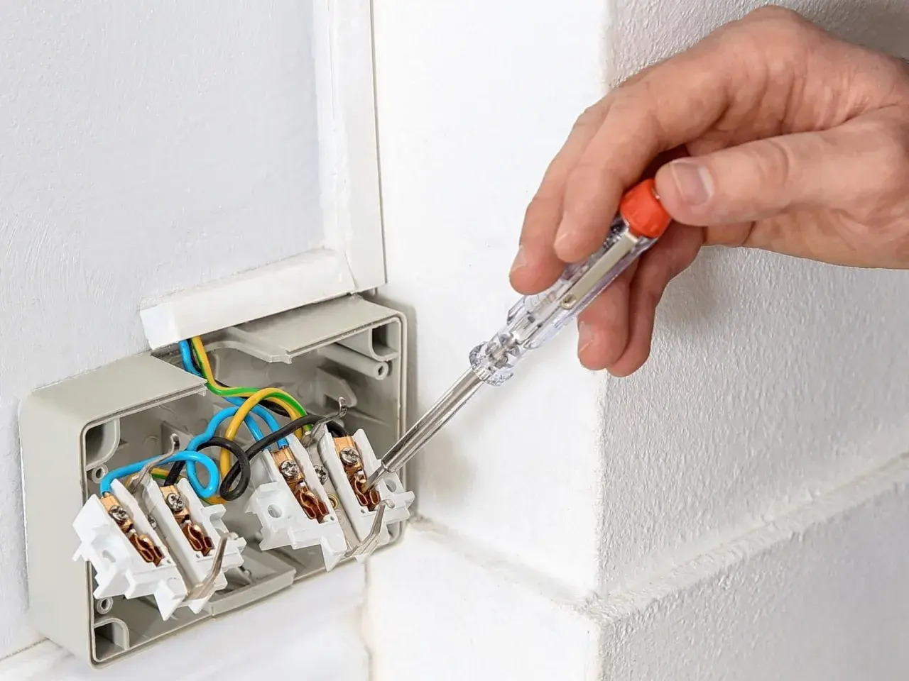 Ręka trzyma próbnik napięcia, sprawdzając instalację elektryczną. Tak działa próbnik napięcia, pomagając w bezpiecznym montażu.