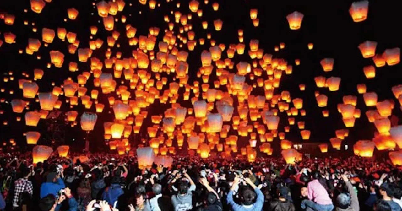 Tysiące lampionów unosi się na nocnym niebie, tworząc magiczny widok podczas święta lampionów. Tłum ludzi obserwuje to widowisko.