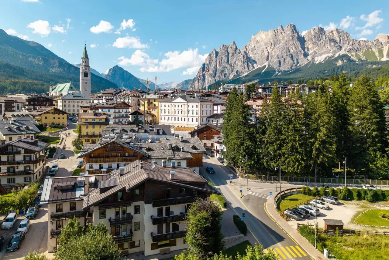 Vue d'un village pittoresque niché au pied des Dolomites en Italie, avec des maisons traditionnelles et une église imposante.