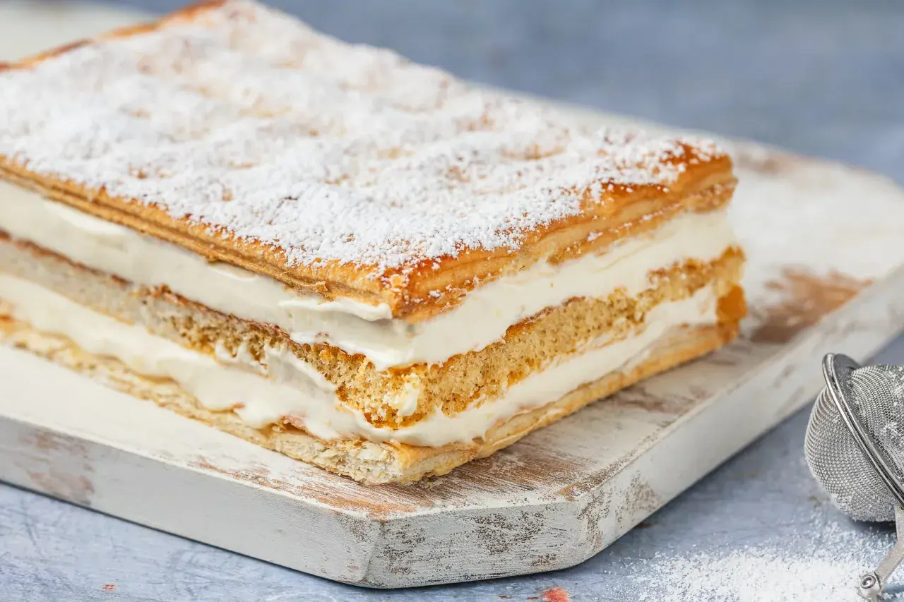 Una deliziosa torta diplomatica, stratificata con soffice crema e sfoglia croccante, spolverata di zucchero a velo.