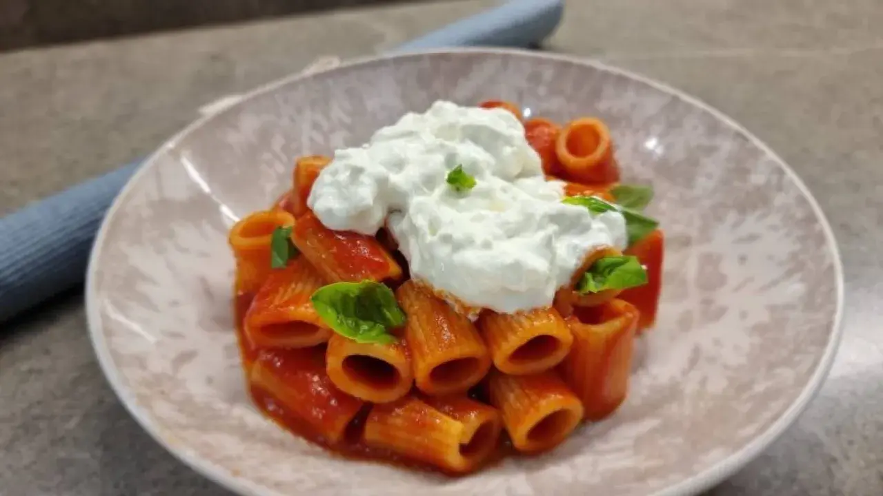 Rigatoni al sugo con abbondante stracciatella cremosa e basilico fresco. Un piatto semplice ma delizioso.