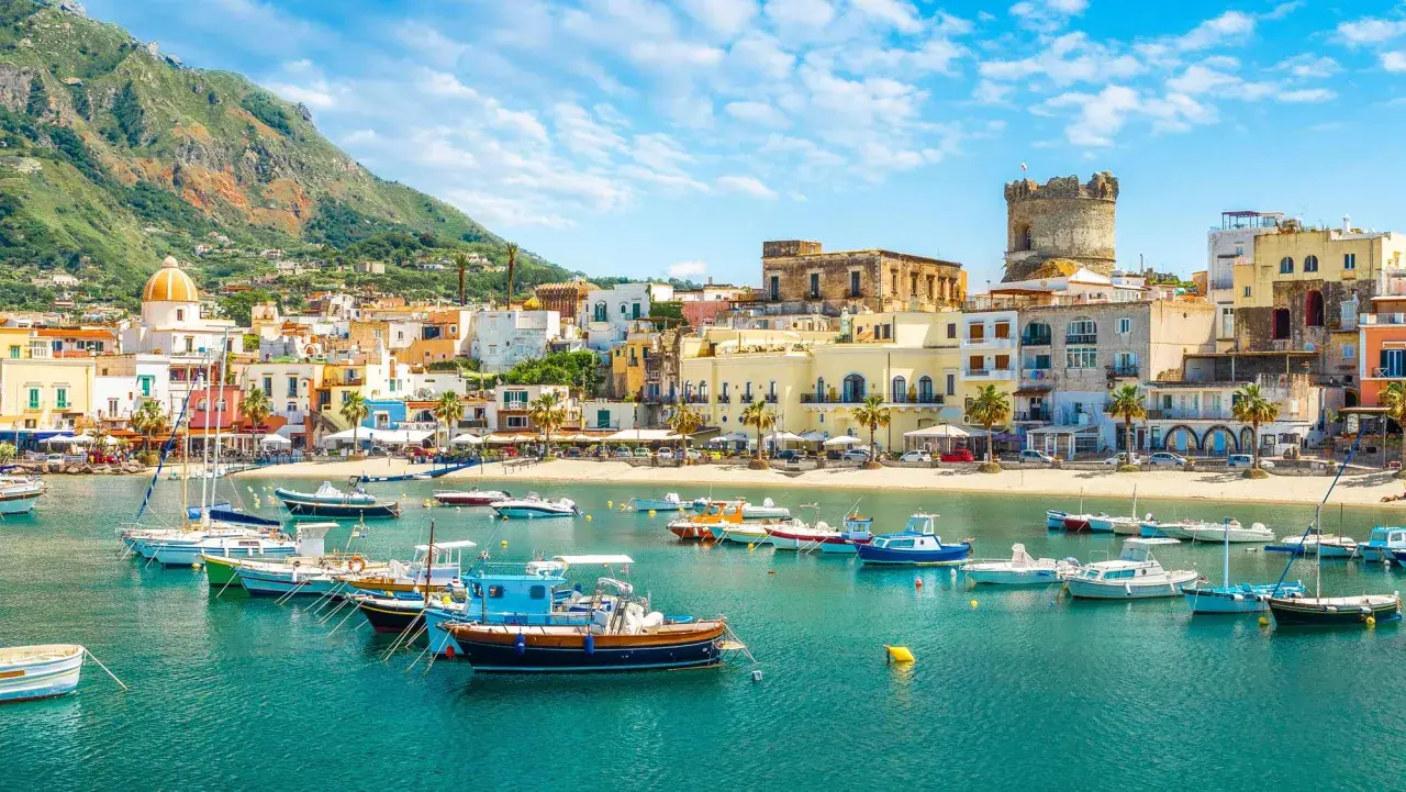 Un borgo marinaro con case colorate, una torre antica e barche nel mare cristallino. Un tuffo nella Ischia storia e bellezza.