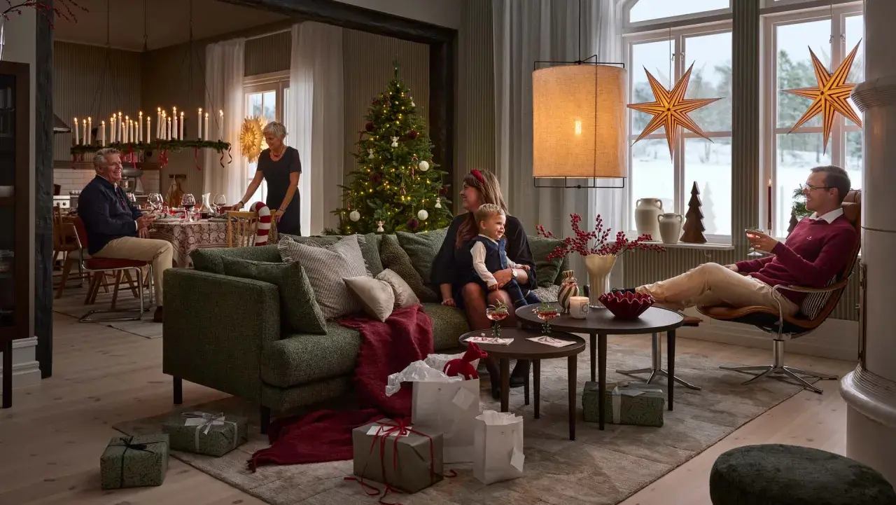 En familj samlas för en mysig jul. Julgranen är klädd, presenter ligger utspridda och ljusen lyser upp rummet.