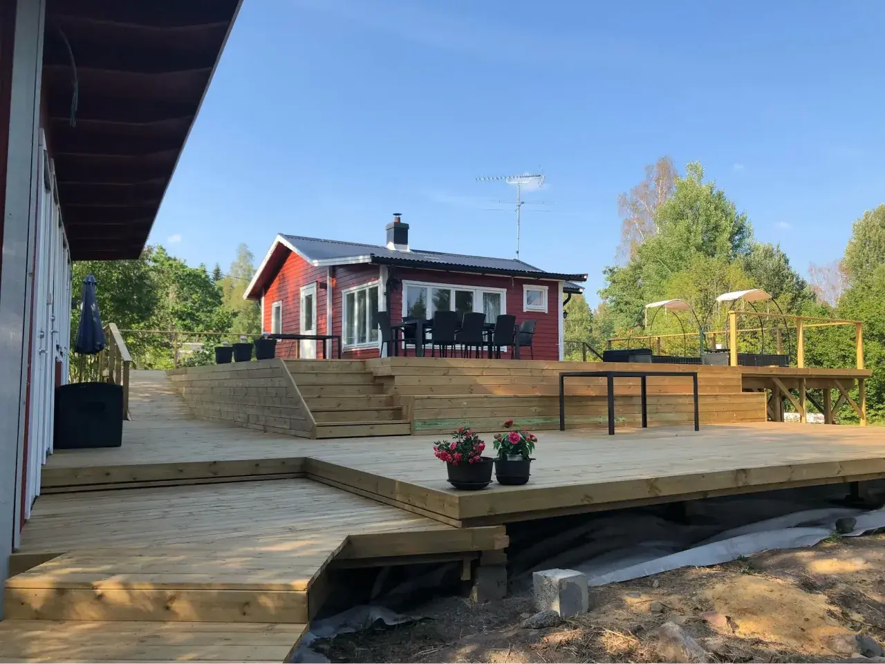 Stor altan runt husknut med trappor och sittplatser. Perfekt för sommarens grillkvällar.