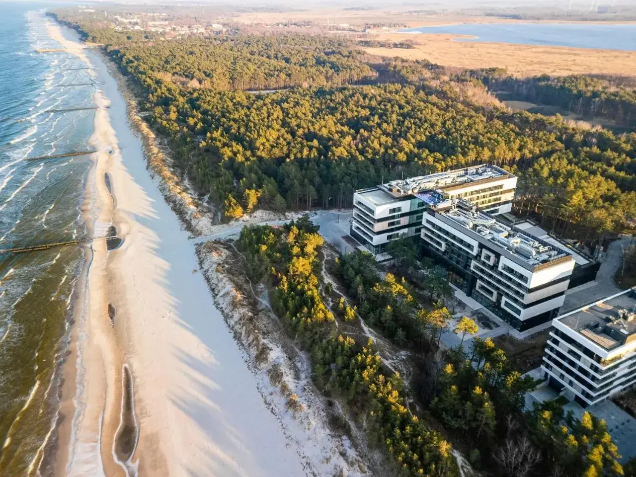 Traumhafter **Polen Urlaub** an der Ostsee: Moderne Hotels neben einem breiten Sandstrand und Kiefernwald.