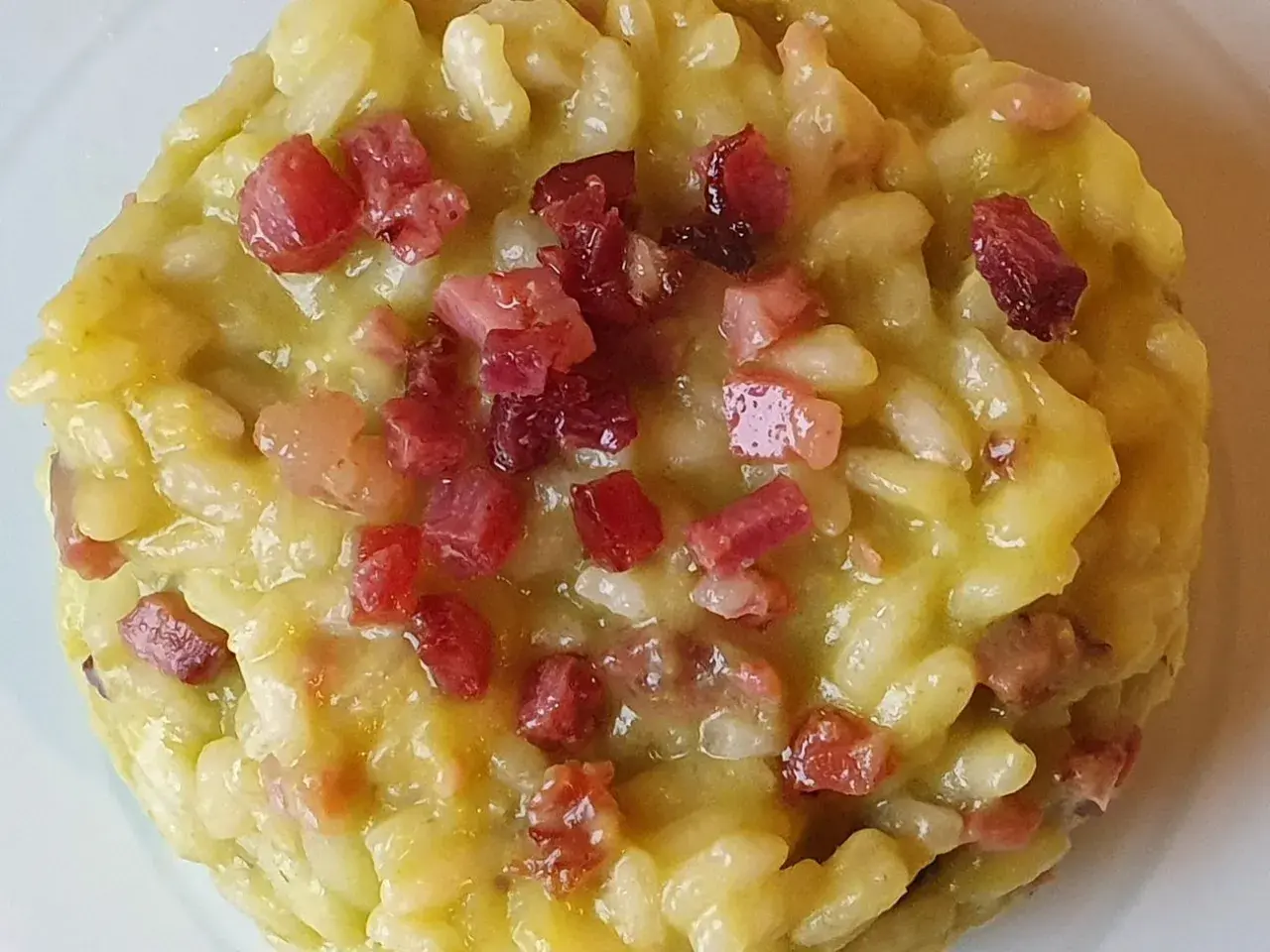 Un cremoso risotto con asparagi e pancetta croccante, un piatto ricco di sapore e profumo.