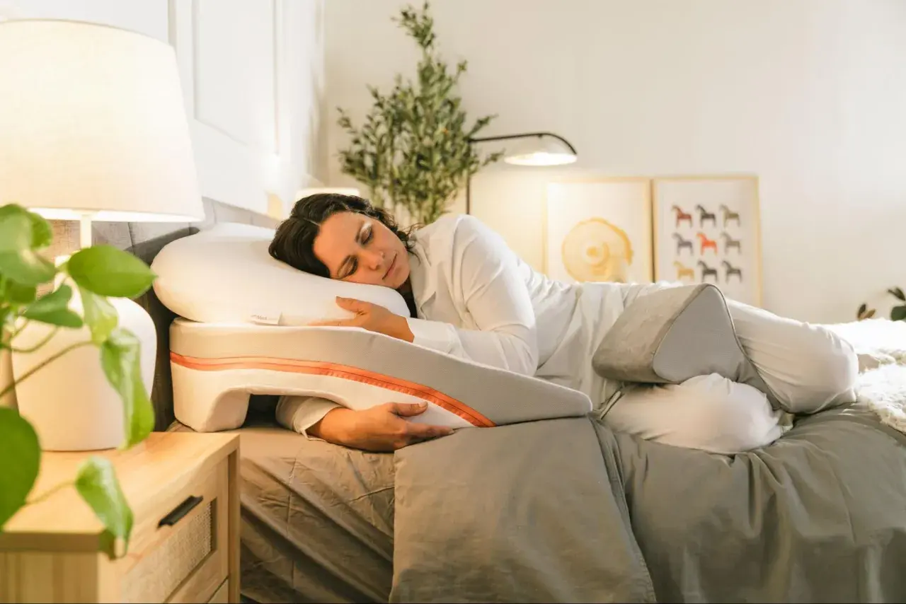 Woman sleeping peacefully on a specialized pillow designed to help with snoring. This pillow offers support for a comfortable sleep position, showing como poner la almohada para no roncar.