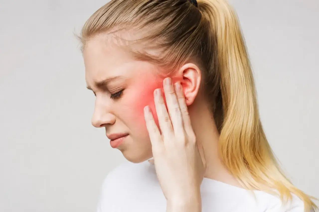 Donna con dolore al viso, area rossa indica possibile nevralgia denti o infiammazione.