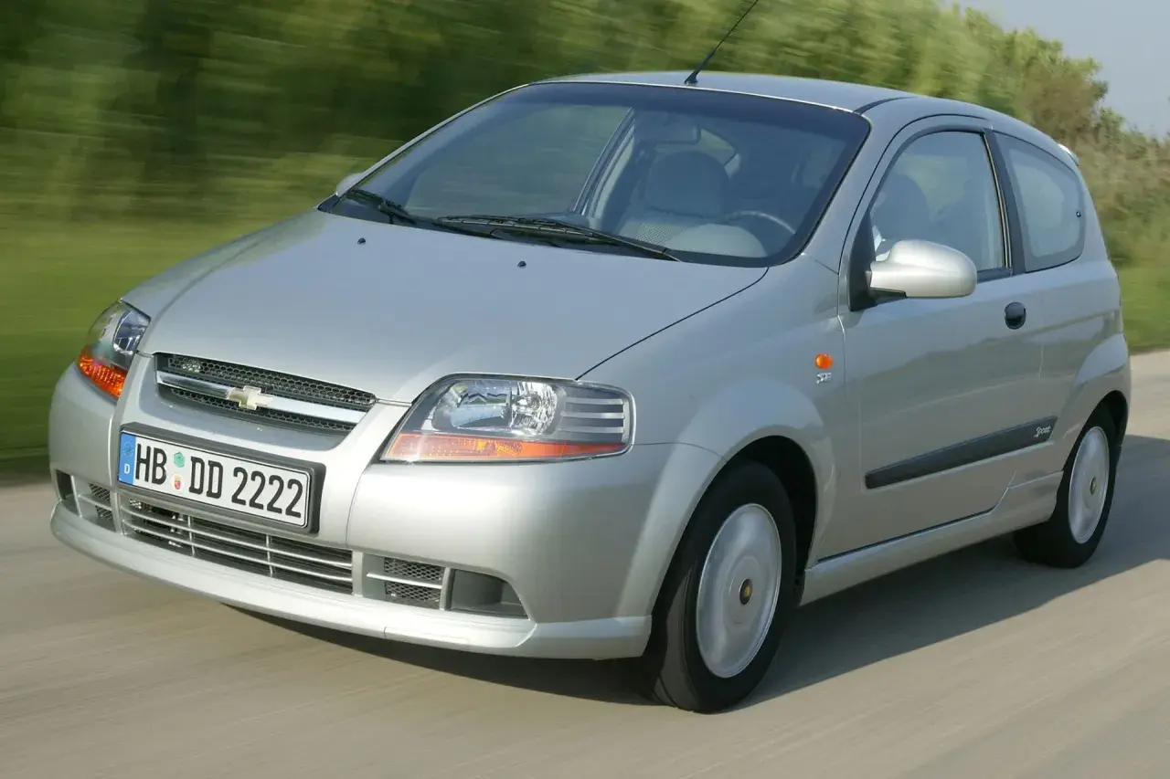 Srebrny Chevrolet Kalos w wersji 3-drzwiowej jedzie po drodze, rozmyte tło sugeruje ruch.