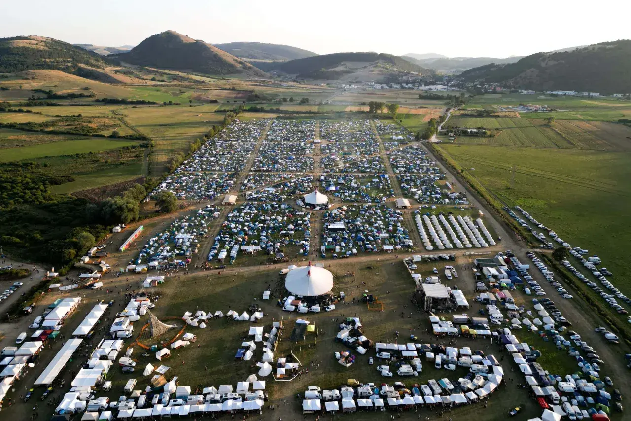 Vasto accampamento di tende e camper per il festival celtico Montelago, immerso in un paesaggio collinare verdeggiante.