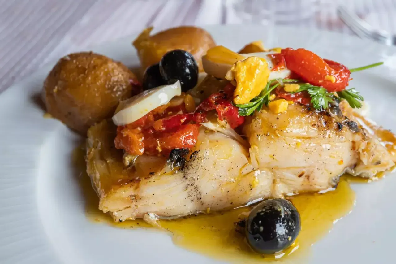 Stoccafisso all'Anconetana con patate, olive nere, pomodorini e uovo sodo. Un piatto ricco e saporito.