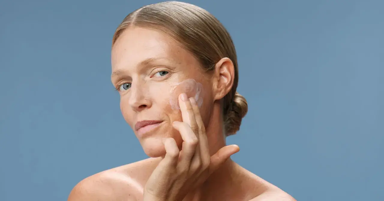 Donna applica crema viso. Scopri a cosa serve il peptide per una pelle radiosa e giovane.