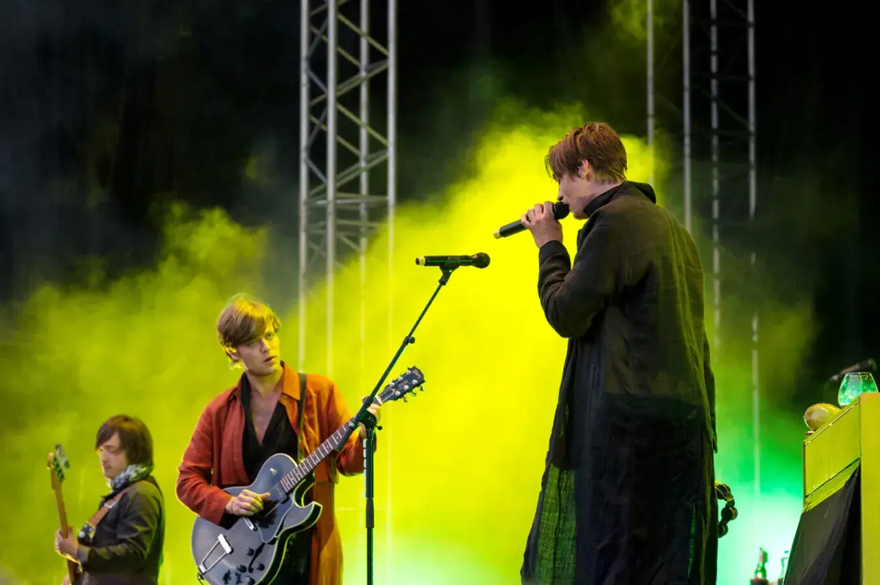 Mando Diao konsert med rök och ljus. Sångaren med mikrofon och gitarristen i röd jacka.