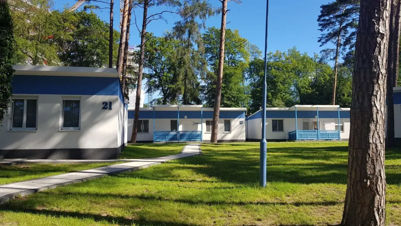 Urocze domki letniskowe w Międzyzdrojach, otoczone zielenią, zapraszają na wypoczynek. Numer 21 widoczny na jednym z budynków.
