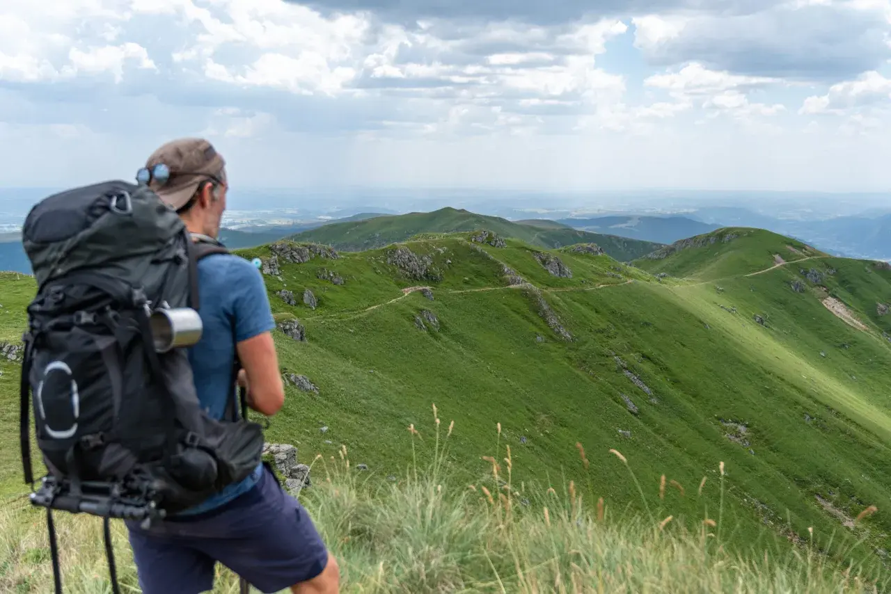 Randonnée Cantal 2 jours : un randonneur admire le paysage verdoyant des monts du Cantal, prêt pour son aventure.
