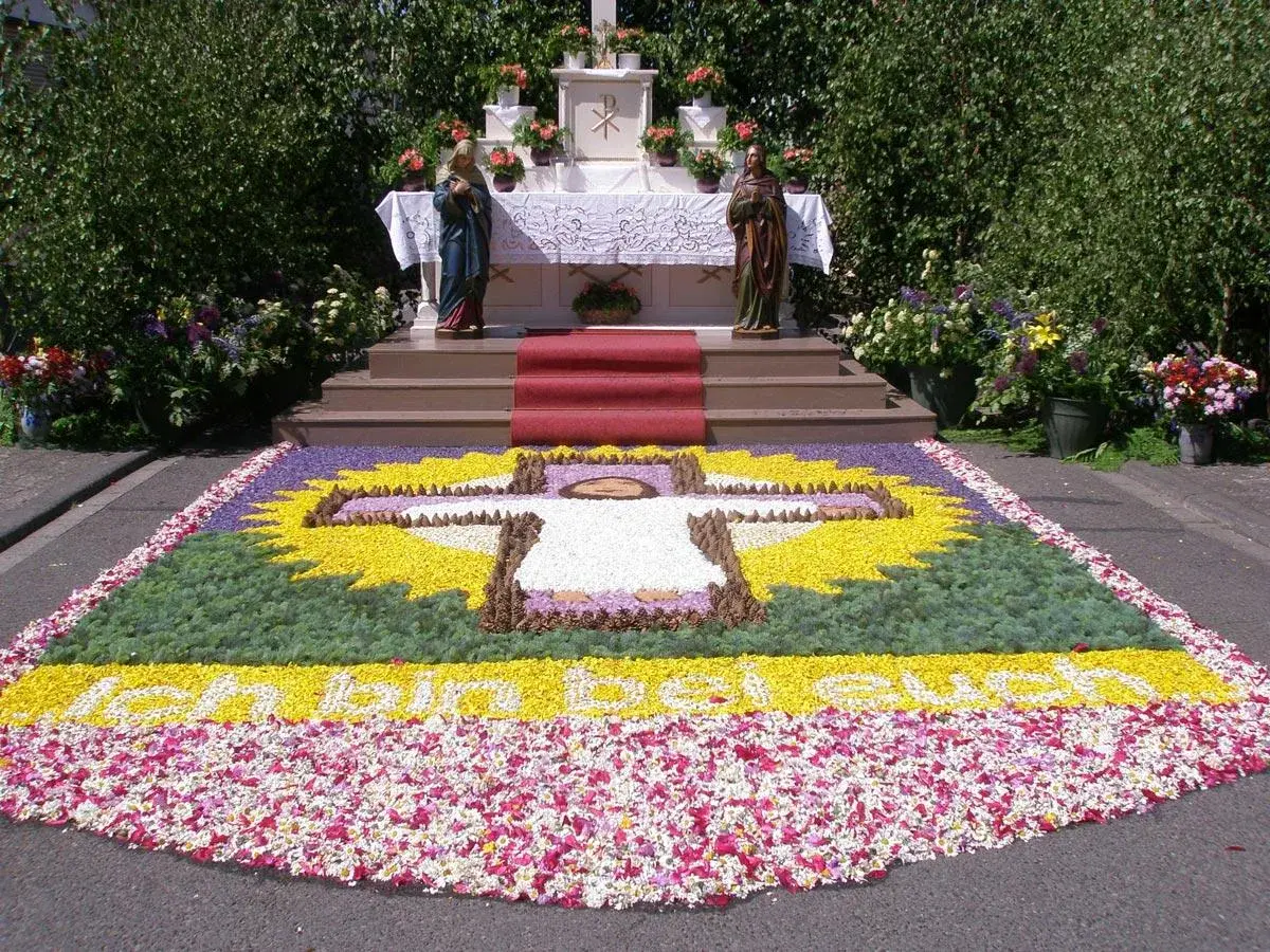 Ein Blumenteppich mit Kreuz und Schriftzug "Ich bin das Brot" erinnert an den Fronleichnam Ursprung.