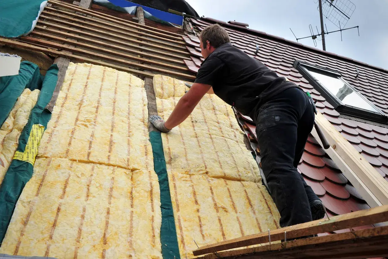 Dachdecker verlegt Dämmung. Energetische Sanierung Pflicht: So wird das Haus winterfest und spart Heizkosten.