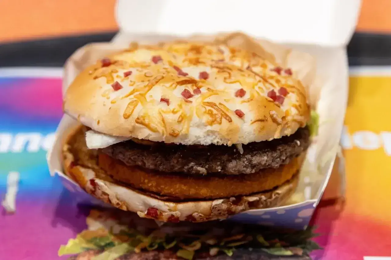 Apetyczny zestaw drwala kcal: soczysty burger z podwójną wołowiną, chrupiącym plackiem ziemniaczanym i bułką posypaną serem i kawałkami boczku.