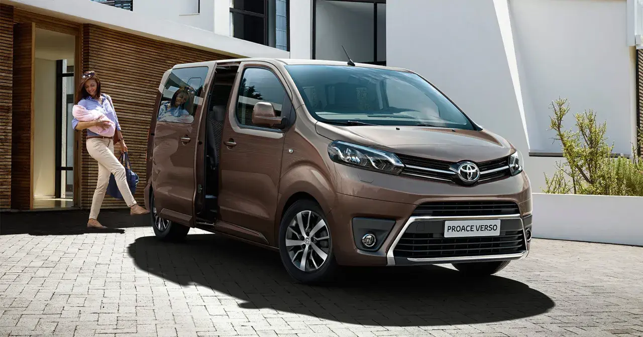 Kobieta z dzieckiem na rękach wsiada do brązowego toyoty van Proace Verso.