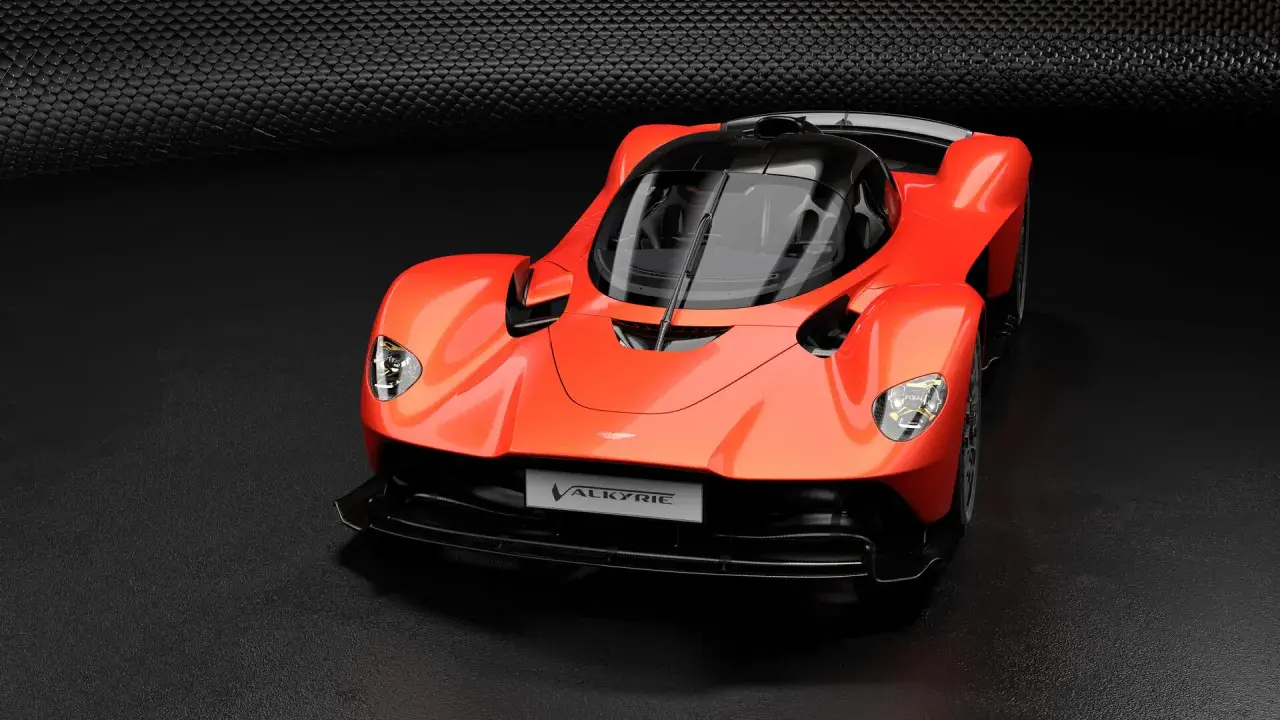 Pomarańczowy Aston Martin Valkyrie, supersamochód o futurystycznym designie, prezentuje swoje aerodynamiczne linie na ciemnym tle.