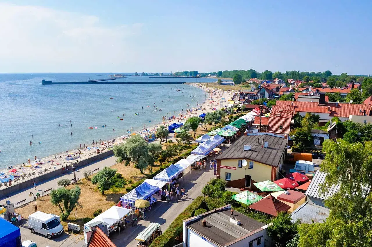 Hel: plaża pełna ludzi, stragany z pamiątkami i jedzeniem, idealne atrakcje dla dzieci.