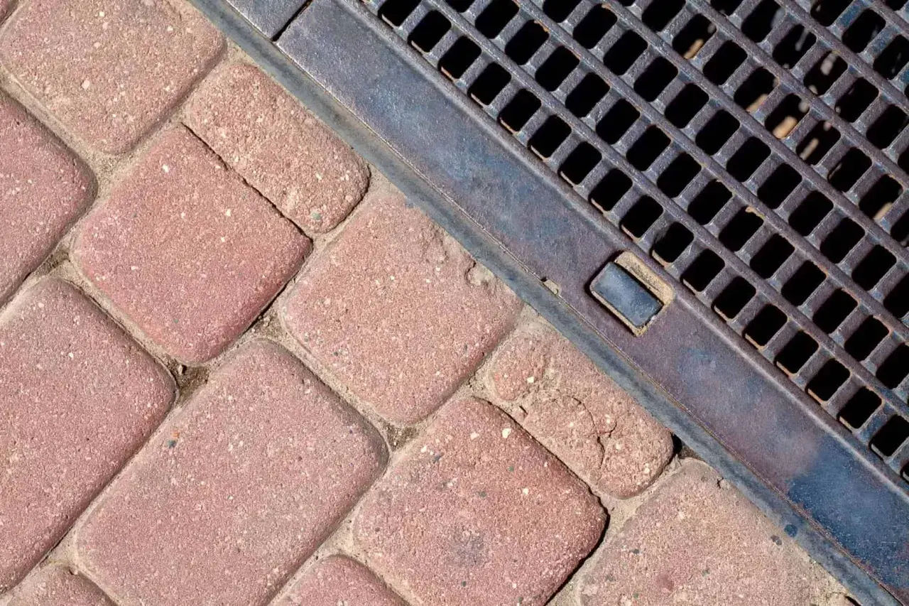 Kostka brukowa i metalowa kratka ściekowa zapewniające sprawne odwodnienie domu.